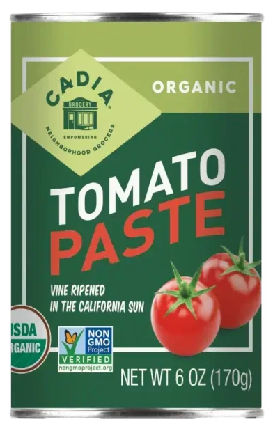 Can of Cadia Organic Tomato Paste with green label and tomato graphics on a white background